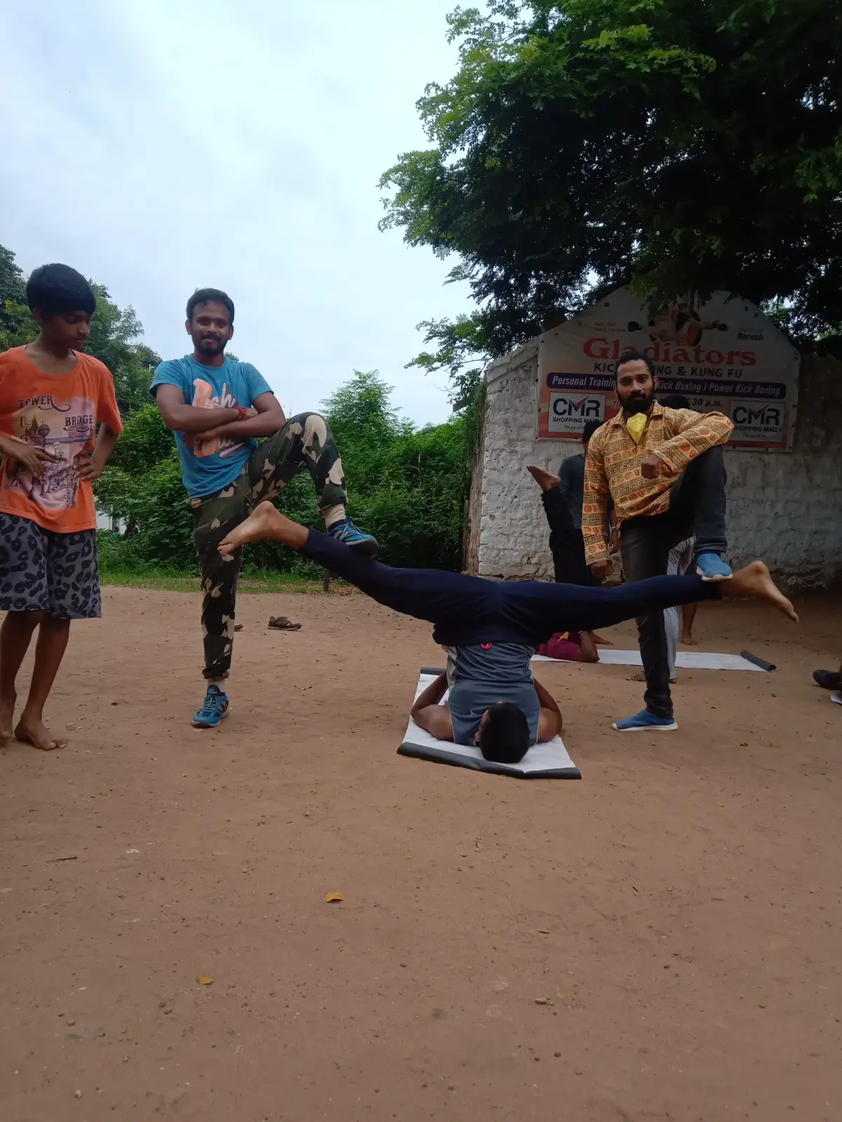 A student balancing upside down in a split while others watch in the yard