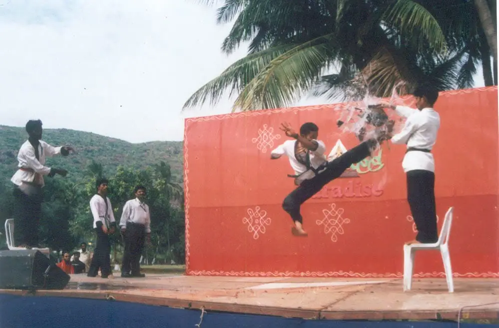 Older film photo of a flying kick breaking tiles at a stage demonstration